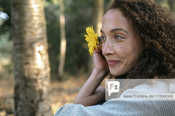 Lächelnde junge Frau mit Blume im Park