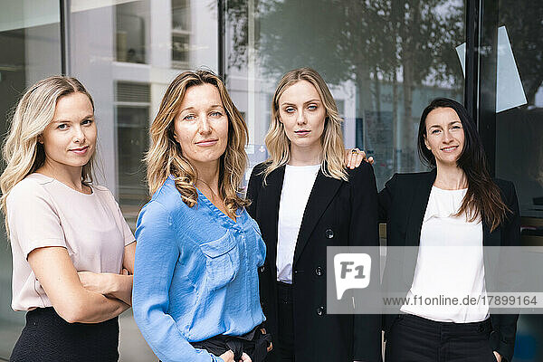 Selbstbewusste Geschäftsfrauen stehen zusammen vor einer Glaswand