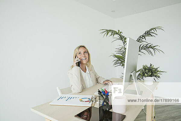 Smiling businesswoman on the phone at desk in office