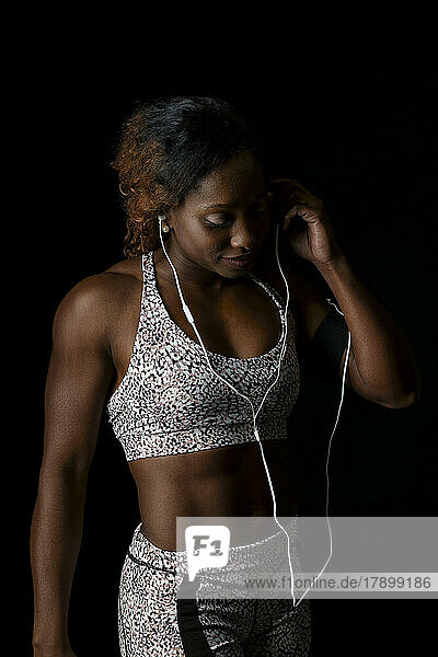 Athlete wearing in-ear headphones against black background