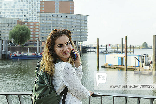 Glückliche Frau  die im Hamburger Hafen telefoniert
