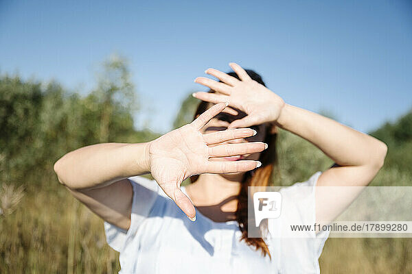 Woman covering face on sunny day