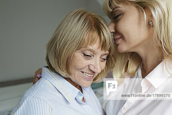 Happy daughter embracing and caring mother at home