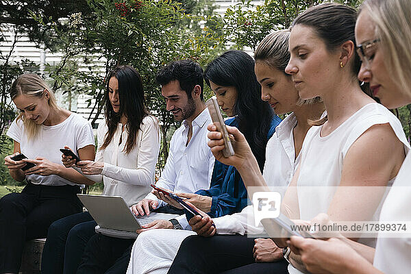 Geschäftskollegen nutzen Smartphone und Laptop und sitzen zusammen im Büropark