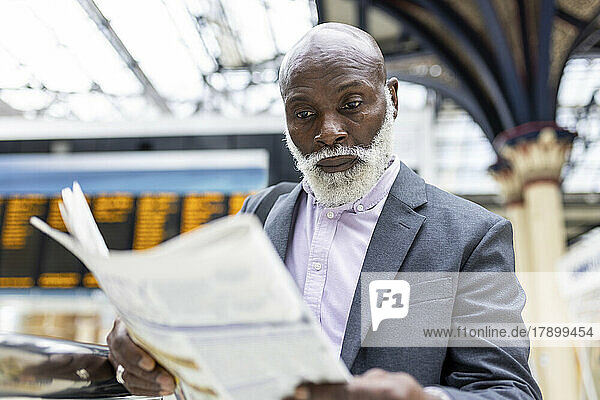 Senior businessman reading newspaper at railroad station