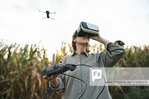 Frau mit VR-Brille und ferngesteuerter Drohne im Maisfeld