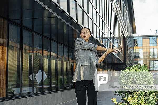 Businesswoman stretching arm at office park