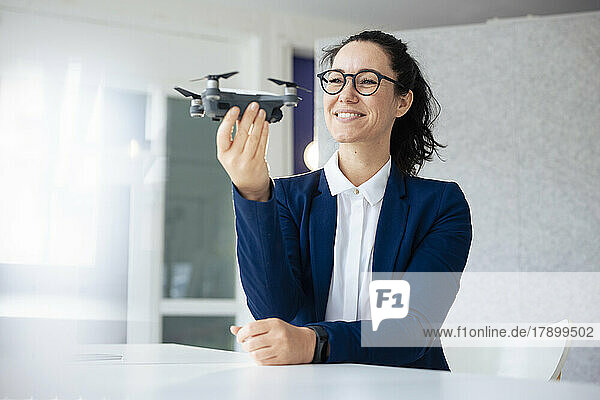 Smiling businesswoman with eyeglasses examining drone
