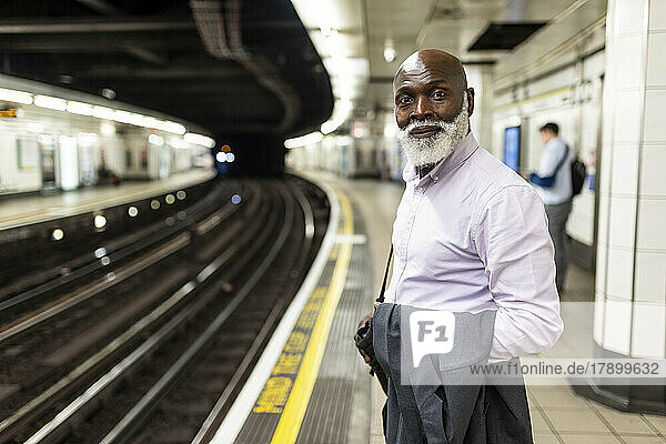 Smiling senior businessman waiting at subway station
