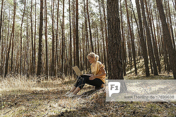 Mature woman using laptop in forest