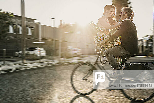Couple enjoying bicycle ride at street on sunny day