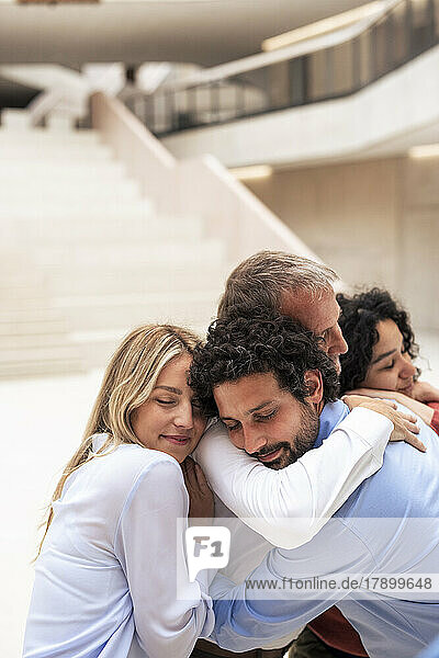 Multiracial businessmen and businesswomen embracing and smiling in lobby