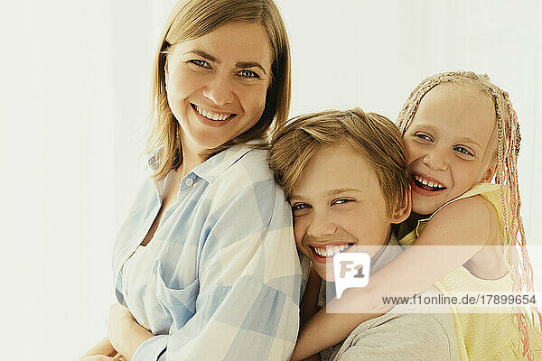 Happy mother with son and daughter spending time together at home