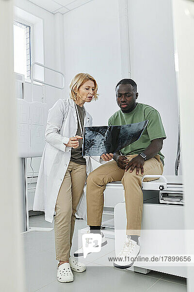 Doctor explaining X-ray to patient sitting in clinic