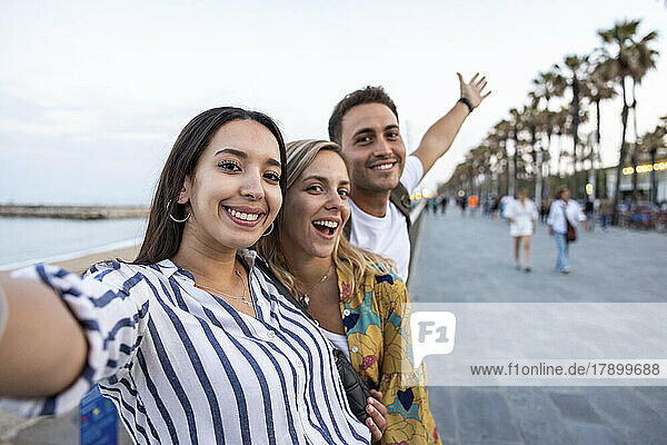 Fröhliche junge Frauen genießen es mit Freunden an der Promenade