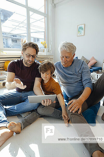 Reifer Mann teilt Tablet-PC mit Sohn und Vater zu Hause