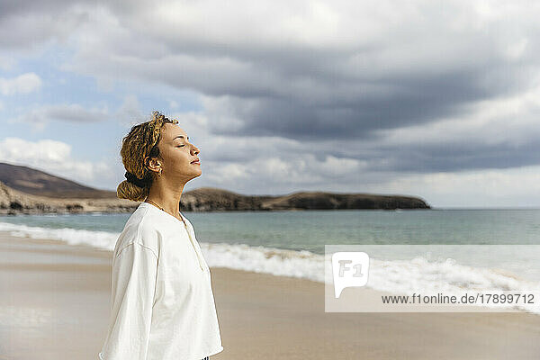 Woman standing with eyes closed at beach