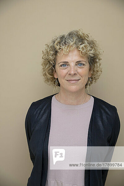 Mature businesswoman standing against brown background