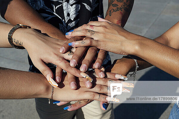 Hand's of friends stacked together on sunny day