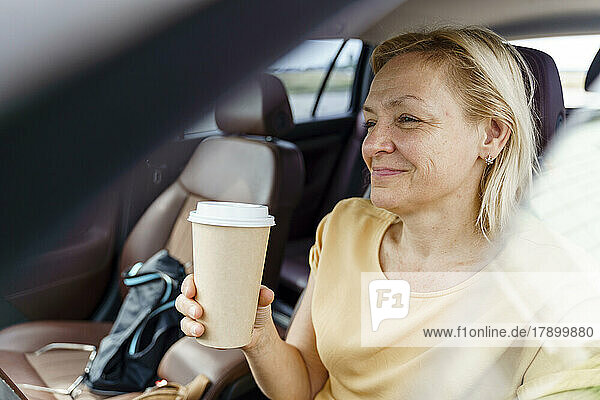 Smiling woman sitting with reusable cup in car