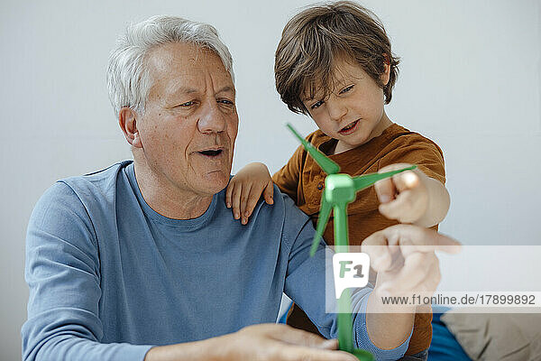 Grandfather and grandson analyzing wind turbine model at home