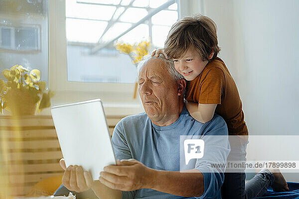 Grandfather taking selfie with grandson through tablet PC at home
