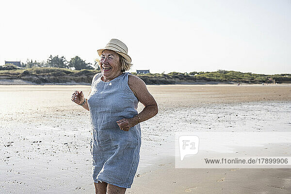 Aktive ältere Frau springt am Strand