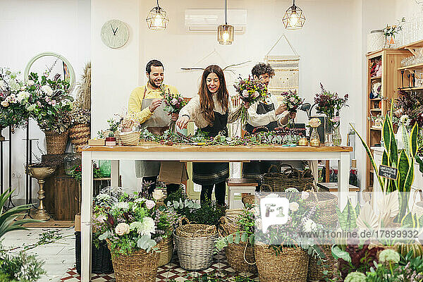 Colleagues making bouquet standing by workbench at flower shop