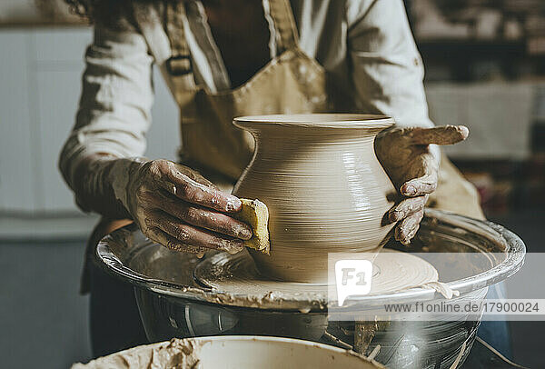 Hands of potter molding pot shape on pottery wheel