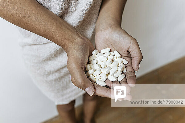 Hands of woman holding pile of pills