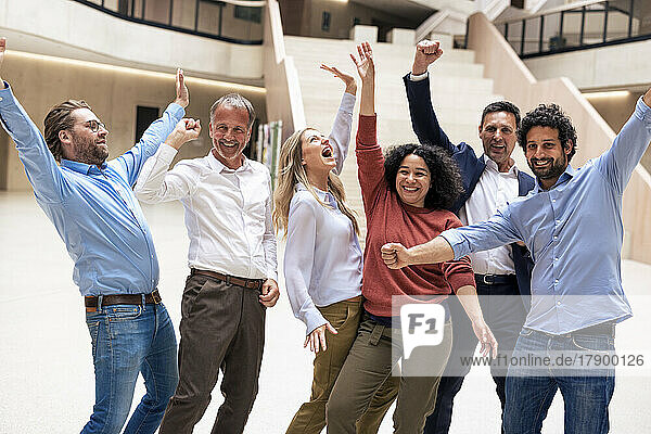 Fröhliche  gemischtrassige Geschäftskollegen feiern den Erfolg in der Lobby