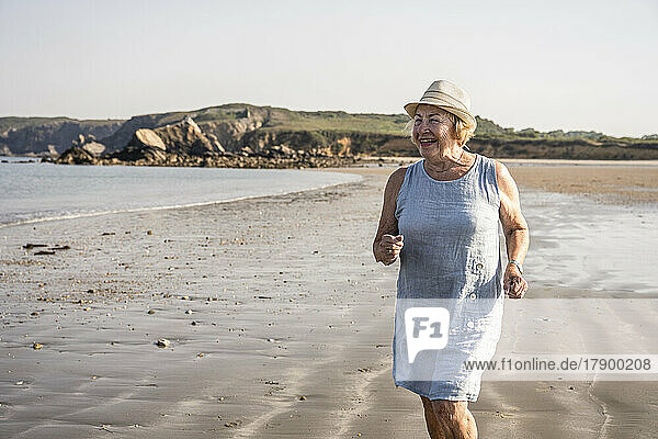 Glückliche ältere Frau mit Hut  die Spaß am Strand hat