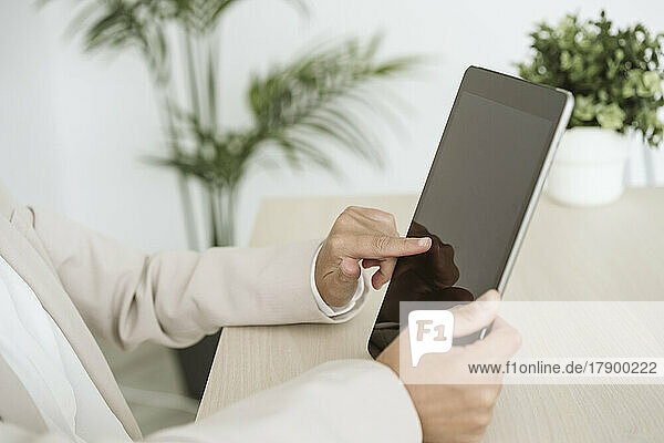 Close-up of businesswoman using tablet PC at desk in office
