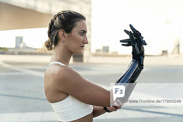 Beautiful young woman looking at arm prosthesis