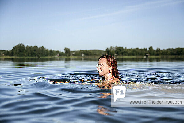 Lächelnde Frau genießt das Schwimmen im See