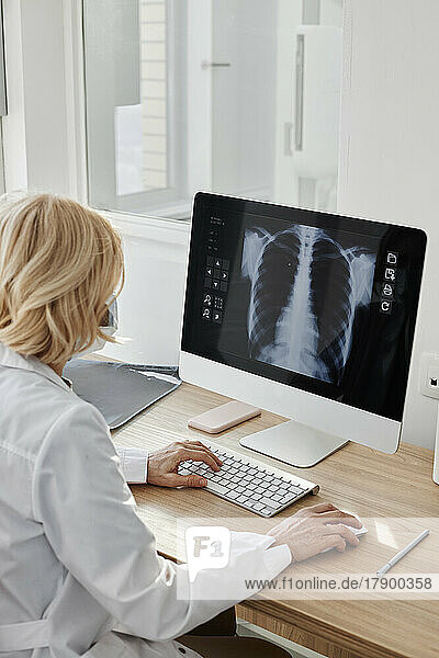 Doctor examining X-ray image on desktop PC in clinic