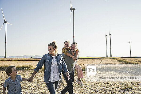 Confident family walking through wind park holding hands