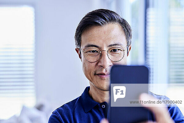 Smiling mature man taking selfie through smart phone