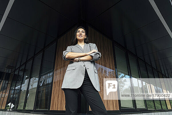 Businesswoman with arms crossed standing outside office building