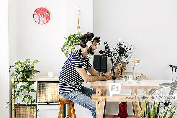 Man wearing wireless headphones recording podcast in home studio