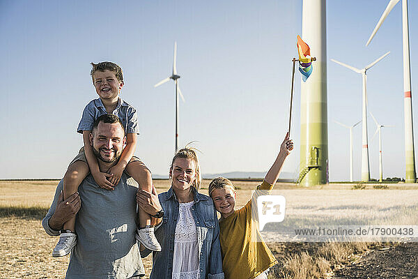 Optimistische Familie steht im Windpark  Tochter trägt buntes Windrad