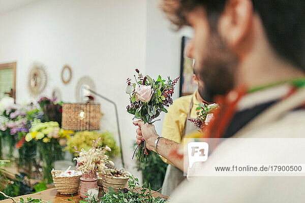 Florist holding bouquet standing with colleague at floral shop
