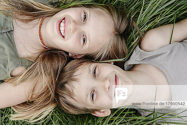 Geschwister liegen zusammen im Gras