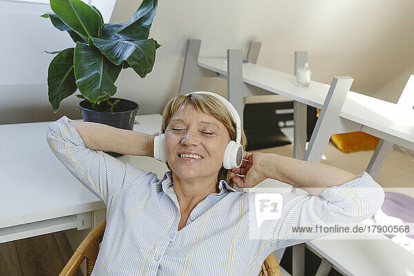 Glückliche ältere Frau  die Musik über drahtlose Kopfhörer hört