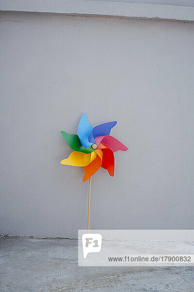 Multi colored pinwheel toy in front of wall