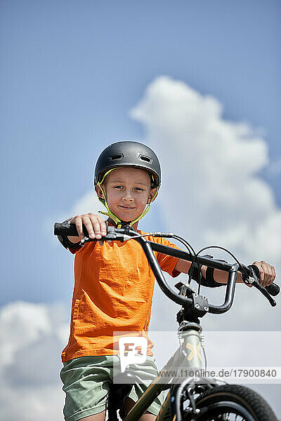 Boy wearing helmet sitting on BMX bike