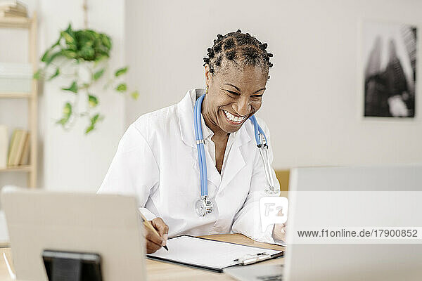Happy doctor talking on video call through laptop at home office