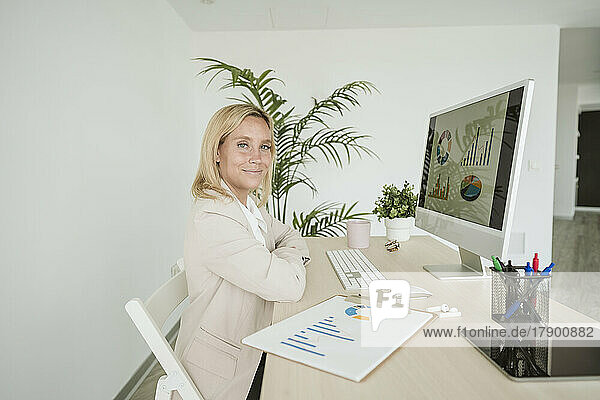 Businesswoman using computer and working on a chart at desk in office