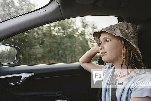 Nettes Mädchen mit Hut  das im Auto unterwegs ist