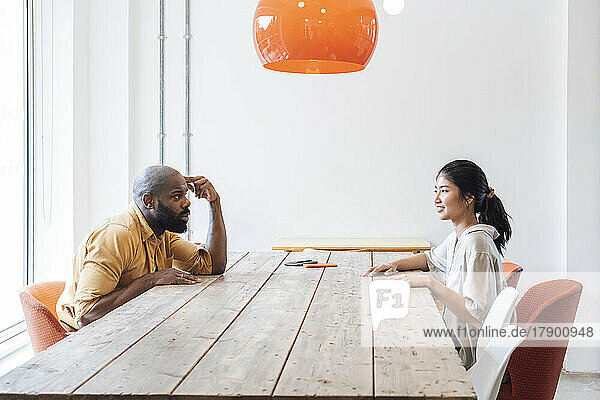 Businessman and woman sitting at office table listening to each other